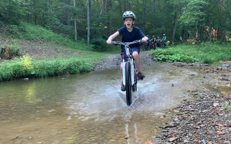 "Student athlete riding across a stream"