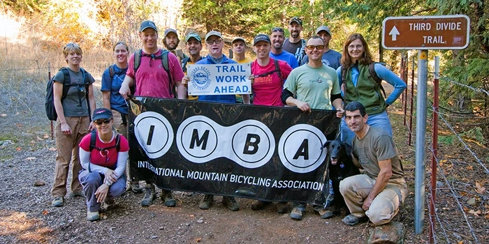 IMBA Local Parnter holding up IMBA Banner and Trail Work Ahead Sign