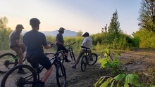 five mountain bikers pause while riding in Maine during sunset